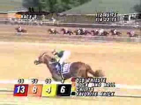 Moment image for Real Quiet triumphs at 1+1⁄4 miles, with jockey Kent Desormeaux, trainer Bob Baffert, and owner Michael E. Pegram.